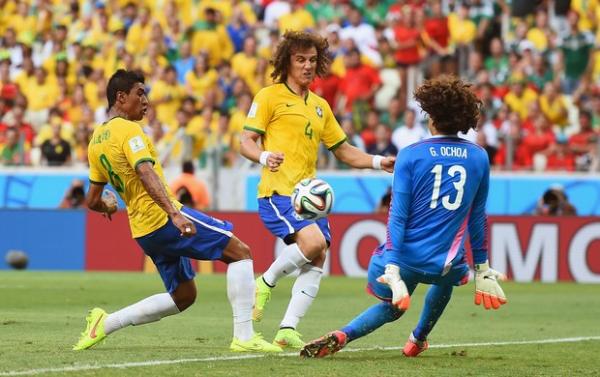 Com os braços junto ao corpo, Ochoa sai do gol e salva conclusão de Paulinho.(Imagem:Getty Images)