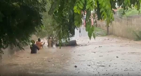 Imagens obtidas pela reportagem mostram a rua totalmente alagada, sem visibilidade do asfalto, e pelo menos seis moradores retirando a mulher do carro.(Imagem:Reprodução)