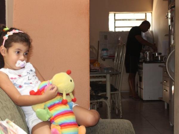 Cledilton faz a comida enquanto a filha assiste TV.(Imagem:Gilcilene Ara&uacute;jo/G1)