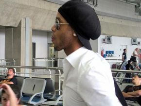 Ronaldinho é escoltado por seguranças até a entrada da porta de embarque