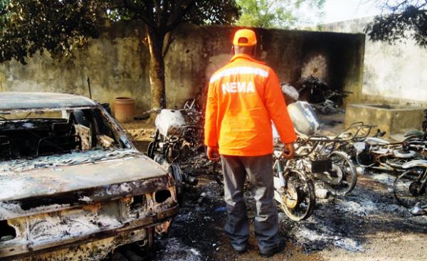 Resgatista observa destro&ccedil;os de carros e motos queimados em ataques no norte da cidade de Kano.(Imagem:Aminu Abubakar/AFP)